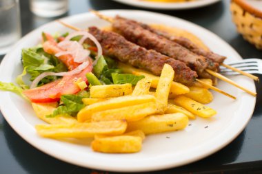 Souvlaki veya şiş patates ve sebze ile üzerinde kebap.