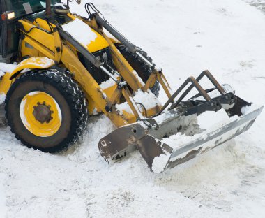 Sokakta kar kürekle traktör.