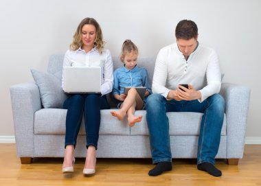 Modern aile değerleri. Baba, anne ve kızı elektronik aygıtlar kullanarak.