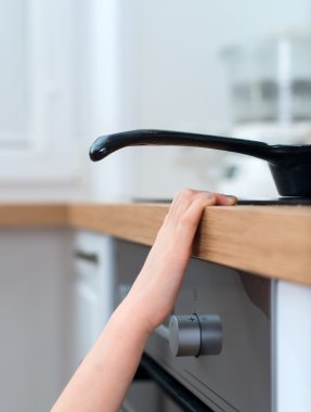 Çocuk soba sıcak tava dokunur. tehlikeli bir durum evde.