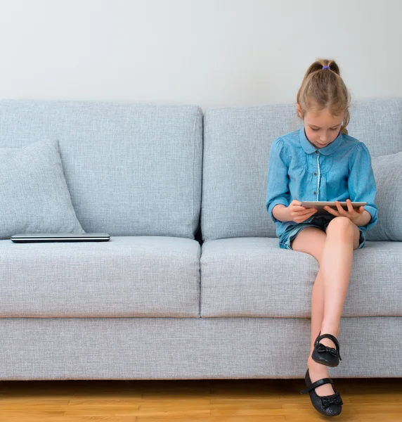 Meisje, zittend op de Bank en de tablet pc gebruiken. Ruimte voor uw tekst. — Stockfoto