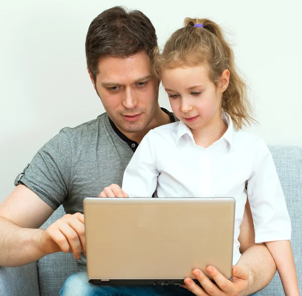 Far och dotter använder bärbar dator hemma. — Stockfoto