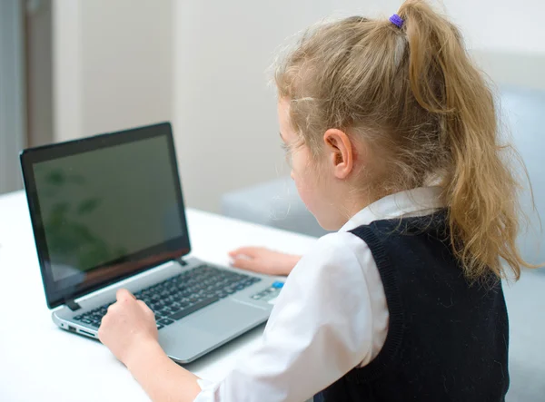 Liten flicka gör sina läxor hemma, med laptop. — Stockfoto