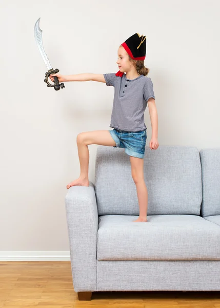 Pirate little girl playing on sofa at home.