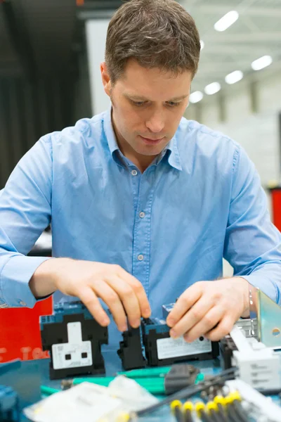 Trabajador guapo ensamblando componentes electrónicos en la fábrica . — Foto de Stock