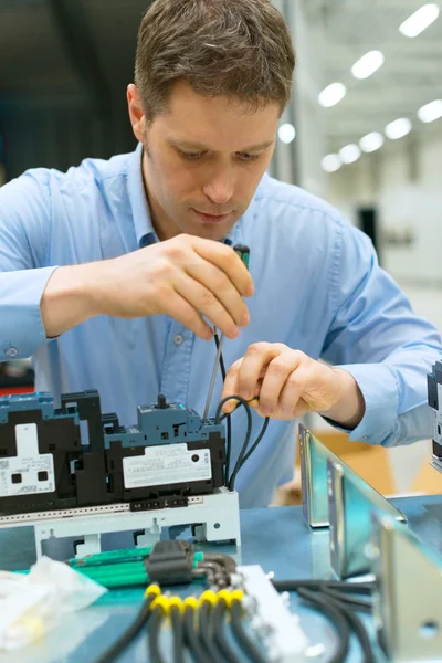 Pohledný dělník montáže elektronických součástek v továrně. — Stock fotografie