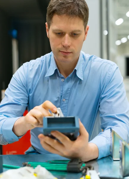 Gutaussehender Arbeiter, der elektronische Komponenten in der Fabrik zusammenbaut. — Stockfoto