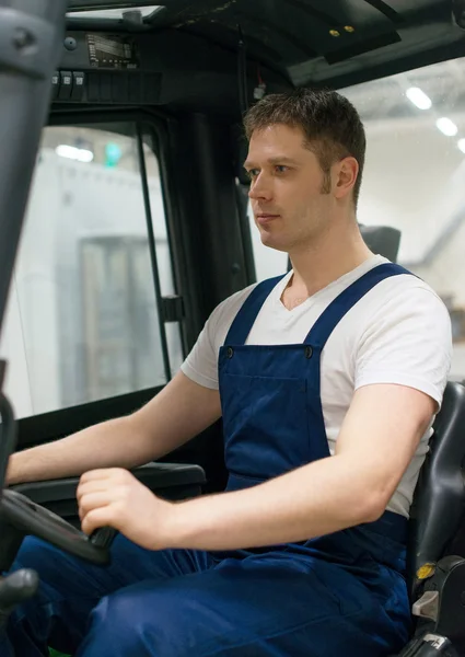 Knappe heftruck operator werkt in het magazijn. — Stockfoto