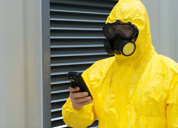 Arbeiter in Chemikalienschutzanzug überprüft Strahlung mit Geigerzähler. — Stockfoto