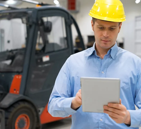 Warehouseman em chapéu duro com tablet pc no armazém . — Fotografia de Stock