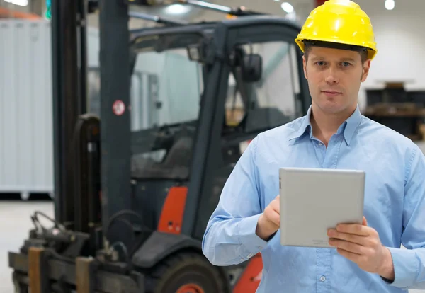 Warehouseman in hard hat with tablet pc at warehouse.