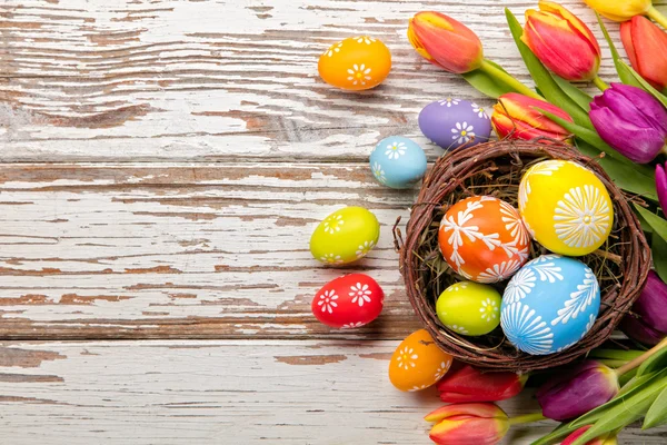 Uova di Pasqua e tulipani su assi di legno — Foto Stock