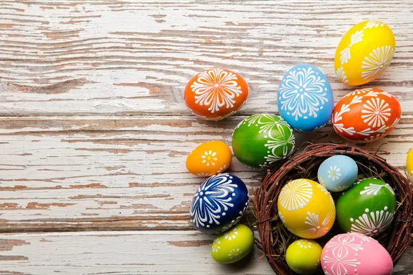 Huevos de Pascua en cesta colocados sobre tablones de madera — Foto de Stock