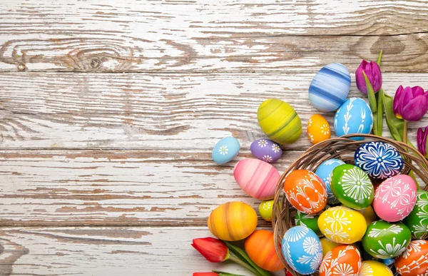 Easter eggs and tulips on wooden planks — Stock Photo, Image