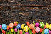 Velikonoční vajíčka a tulipány na dřevěných prknech