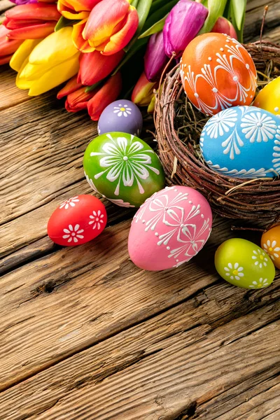 Uova di Pasqua e tulipani su assi di legno — Foto Stock