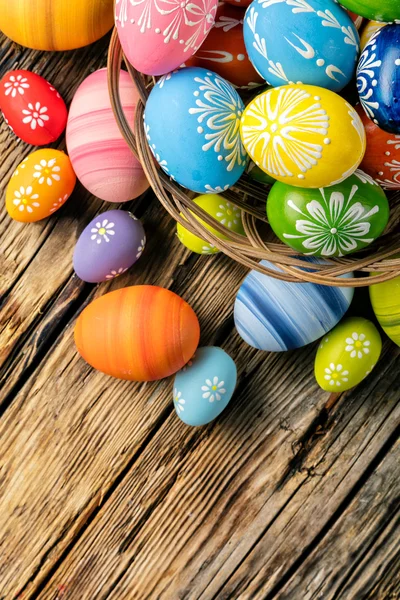 Huevos de Pascua en cesta colocados sobre tablones de madera — Foto de Stock