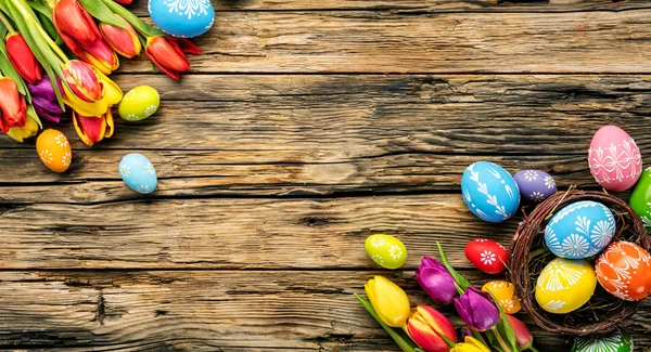 Easter eggs and tulips on wooden planks — Stock Photo, Image