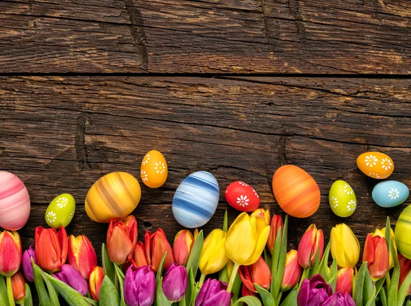 Ovos de Páscoa e tulipas em tábuas de madeira — Fotografia de Stock