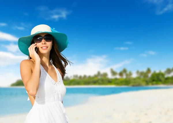 Ung kvinna med mobiltelefon på en strand — Stockfoto