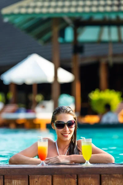 Brunette girl with cocktails in swimming pool — Stock Photo, Image