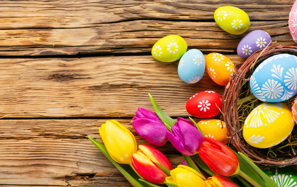 Easter eggs and tulips on wooden background