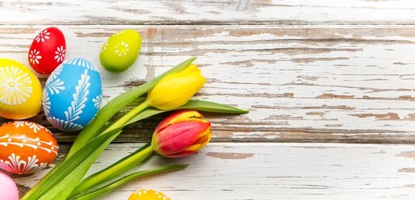 Jaja wielkanocne i tulipany na drewnianym tle — Zdjęcie stockowe