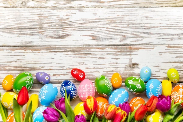 Oeufs de Pâques et tulipes sur fond en bois — Photo