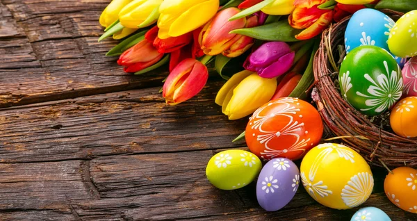 Uova di Pasqua e tulipani su assi di legno — Foto Stock