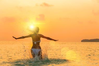 Kız sahilde günbatımı atlama