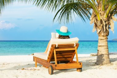 Woman relaxing and reading on deckchair clipart