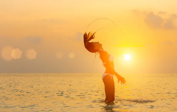 女孩在日落时分在沙滩上跳跃 — 图库照片