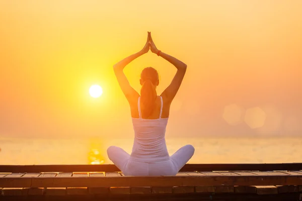 Junge Frau praktiziert Yoga am Strand bei Sonnenuntergang — Stockfoto