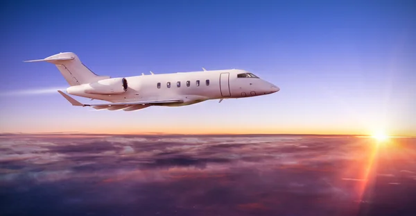 Aereo jet privato che vola sopra le nuvole al tramonto — Foto Stock