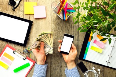 Amerikan doları ve akıllı telefon tutan adamın elleri
