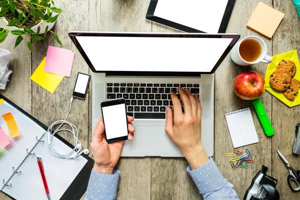 Hands of a man using laptop and smartphone — Stock Photo, Image