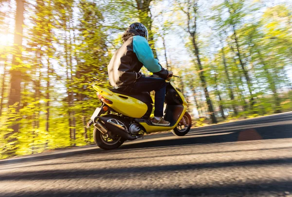 Homem jovem dirigindo scooter, movimento borrão — Fotografia de Stock