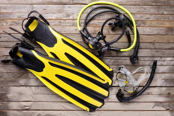 Mask, fins, snorkel and regulator on wooden desk — Stock Photo, Image