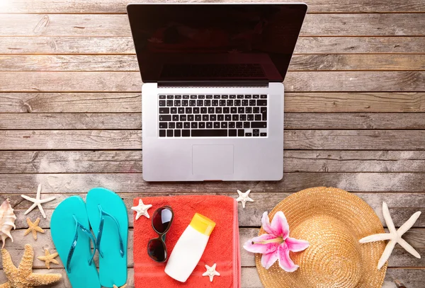 Laptop with beach accessories on wood deck — Stock Photo, Image