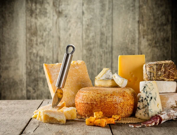 Varios tipos de queso colocados en la mesa de madera — Foto de Stock