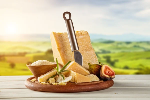 Queijo parmesão sobre tábua de corte colocada sobre madeira — Fotografia de Stock