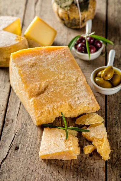 Queijo parmesão sobre tábua de corte colocada sobre madeira — Fotografia de Stock