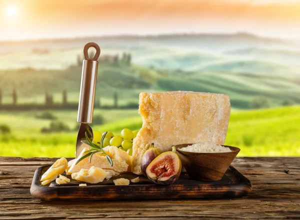 Queijo parmesão sobre tábua de corte colocada sobre madeira — Fotografia de Stock