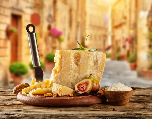 Parmesan cheese on cutting board placed on wood — Stock Photo, Image