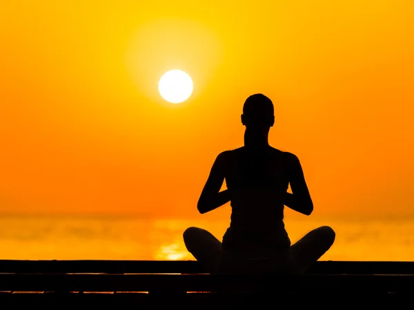 Silueta de mujer joven practicando yoga — Foto de Stock