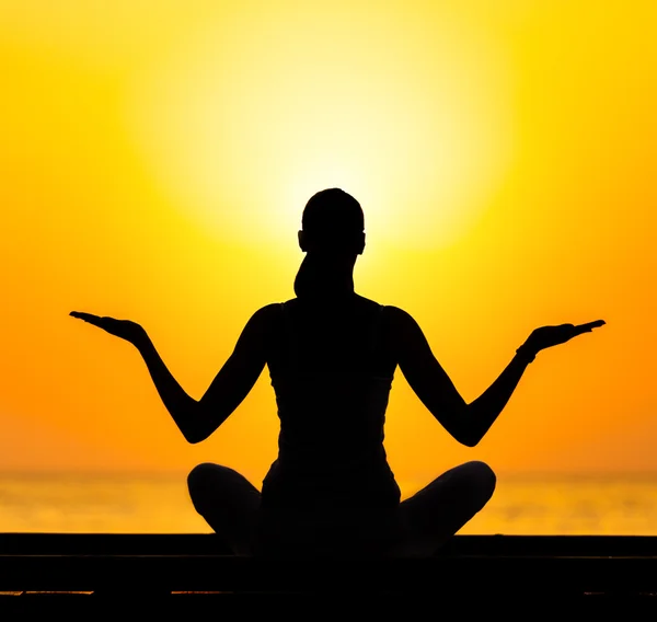 Silueta de mujer joven practicando yoga — Foto de Stock