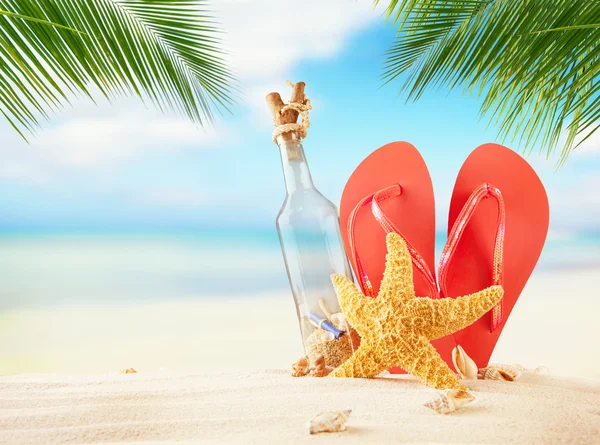 Летний пляж с сандалиями и пустым стаканом — стоковое фото
