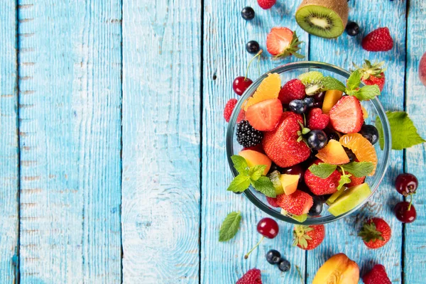 Ahşap masa üzerinde sunulan taze meyve salatası — Stok fotoğraf