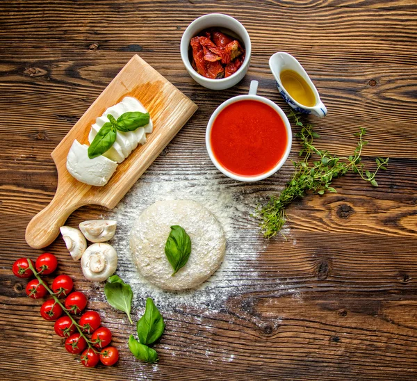 Тісто для піци з томатним соусом на дерев'яному столі — стокове фото