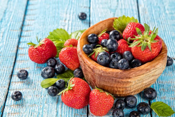 Bessen fruit in schoteltje gelegd op oude houten planken — Stockfoto